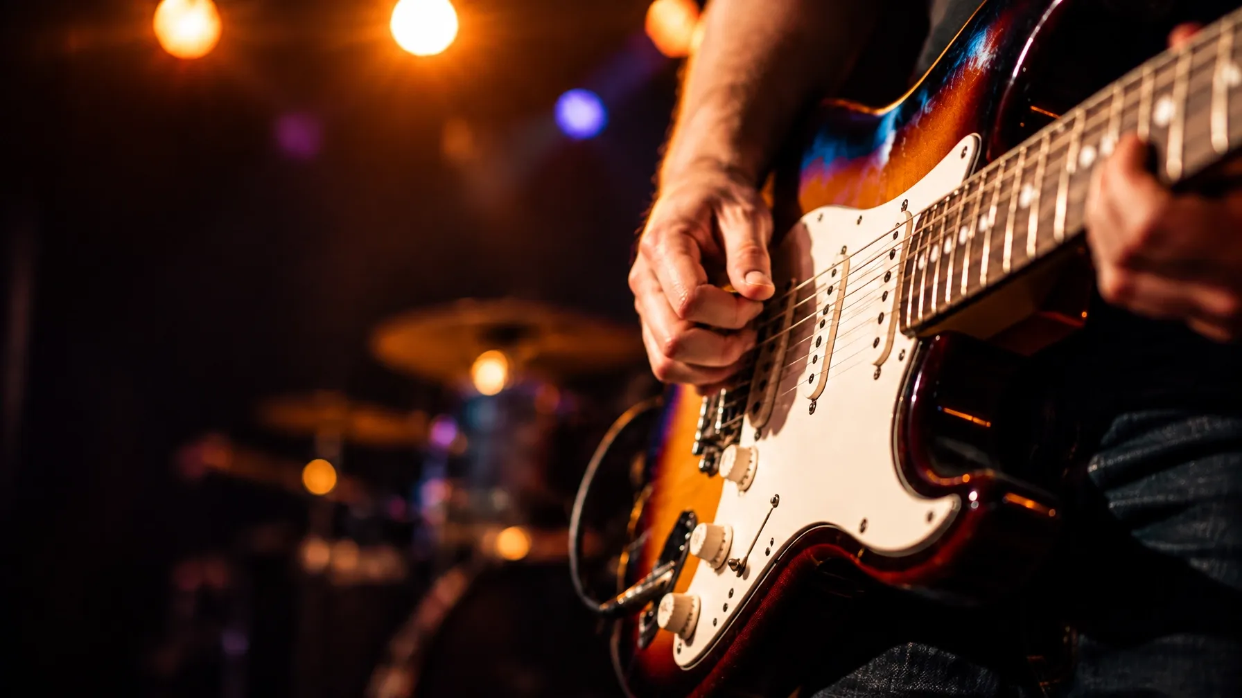 Hands playing an electric guitar under warm stage lights